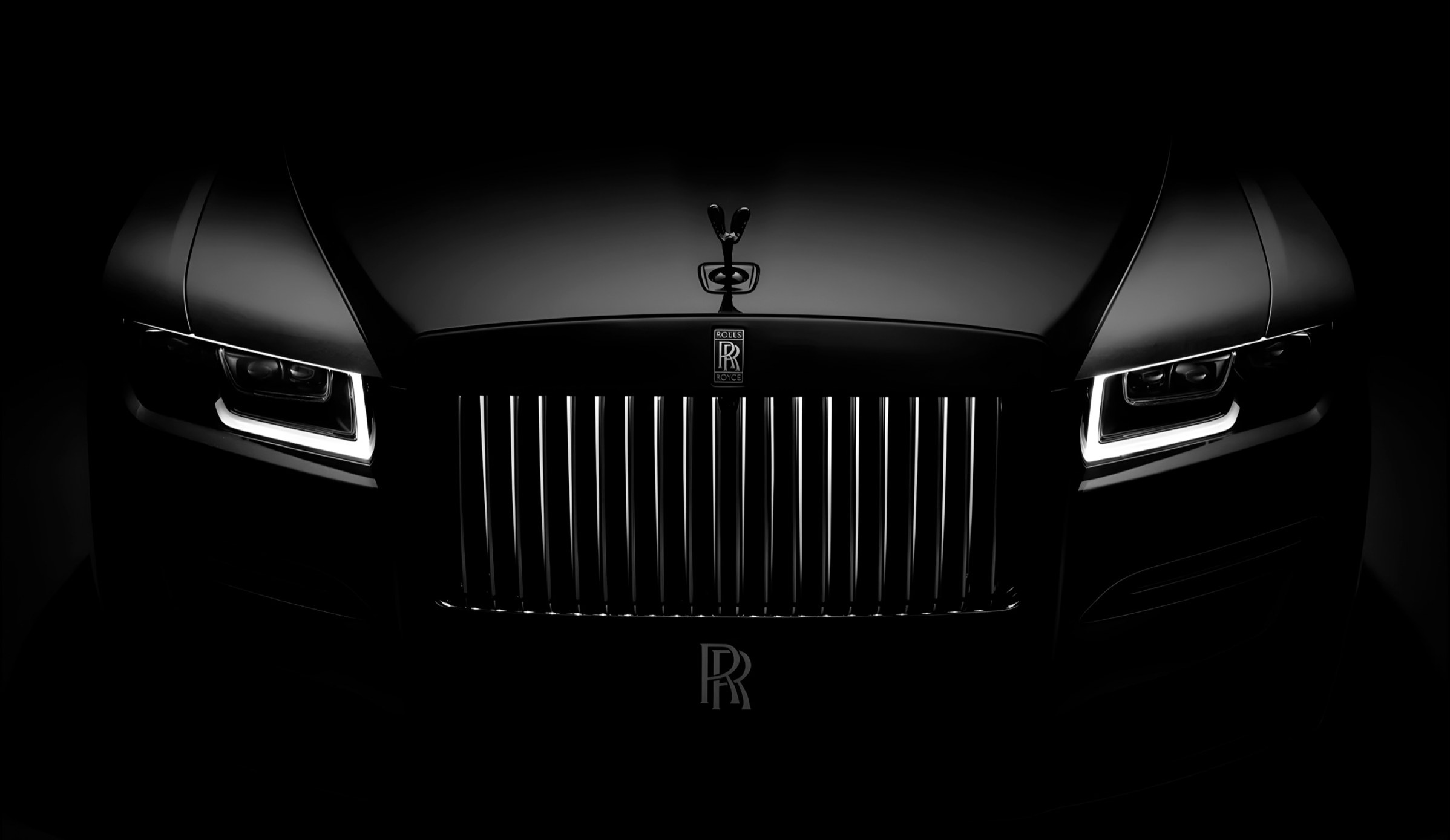 The Rolls-Royce Black Badge, head-on, grille lit against the dark